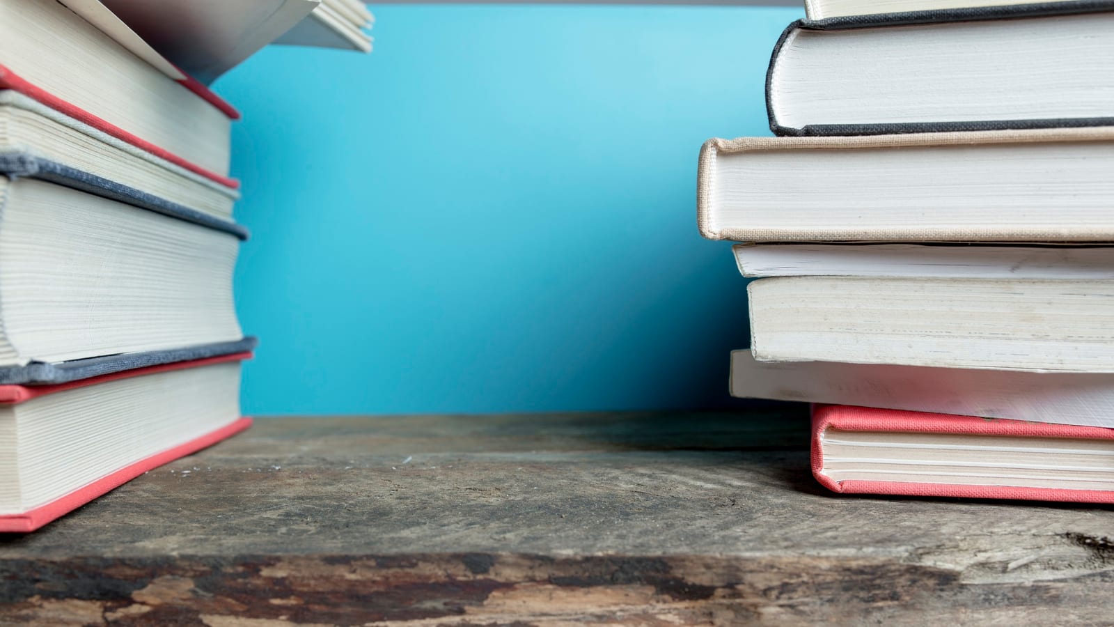 Duas pilhas de livros de capa dura em close, com um fundo azul.